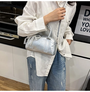 Gros plan du sac argenté style Y2K avec chaîne en perles et détail de nœud en dentelle