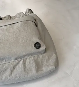 Detailed macro view of nylon fabric texture and round metal logo buckle on a bucket bag