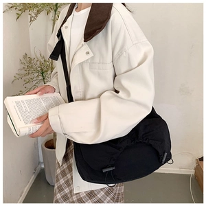 Grande borsa a tracolla in nylon nero abbinata a un outfit casual e gonna scozzese