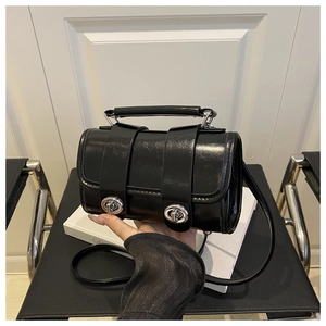 Détail du sac Boston noir brillant avec fermoirs rotatifs argentés et poignée chic