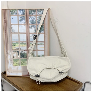 Dettaglio borsa a tracolla in nylon crema con coulisse regolabili su base in legno