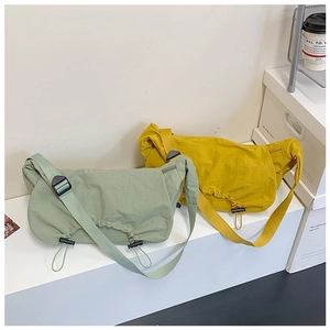 Dettaglio di grandi borse a tracolla in nylon verde e giallo con coulisse regolabile