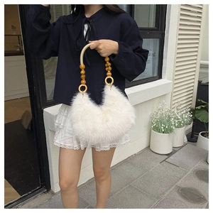 Detail view of plush white faux fur handbag with wooden bead handles and crescent shape