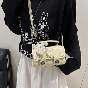 Bolso Boston crema con encaje, lazo y colgante de perla corazón mostrado en modelo