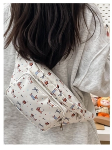 Rear view of white crossbody bag featuring colorful cartoon dog prints and silver zippers