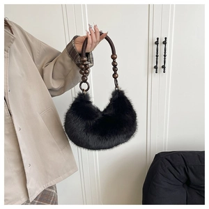 Detail view of black faux fur crescent bag featuring decorative dark wooden beads on strap