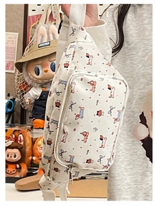 Close-up of white crossbody bag featuring colorful cartoon dog patterns and zip pockets