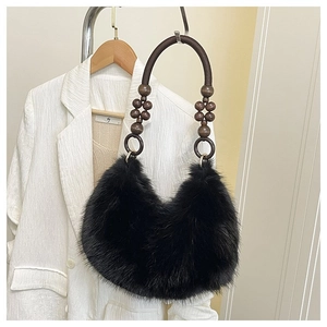 Detail of plush black faux fur handbag with beaded woven strap against white blazer