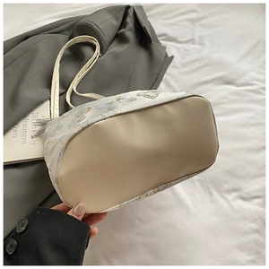 Detailed embroidery of butterflies on white tote bag with faux leather bottom