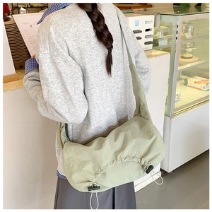Dettaglio della borsa a tracolla in nylon verde chiaro con pieghe a coulisse e tracolla larga
