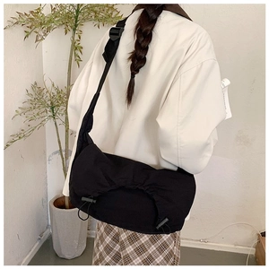 Dettaglio della borsa a tracolla in nylon nero con coulisse e tracolla regolabile sul modello