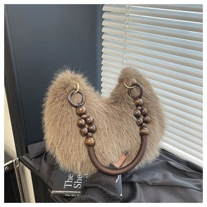 Detail of plush faux fur texture and unique beaded handle on a brown fuzzy handbag