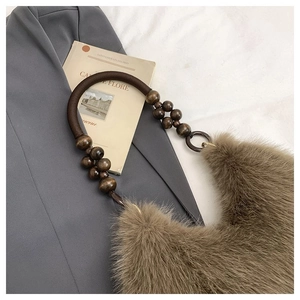 Detail of faux fur shoulder bag with beaded wooden handle on textured fabric and suit