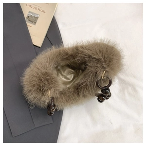 Detail of tan faux fur handbag featuring round wooden beaded handle and plush texture