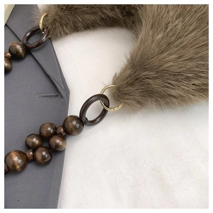 Close-up of faux fur shoulder bag with vintage wooden beads and golden metal buckles