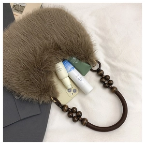 Detail of plush brown crescent bag with beaded handle and essentials inside