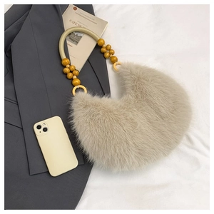 Detail of beaded handle and gold metal ring on a beige faux fur crescent handbag