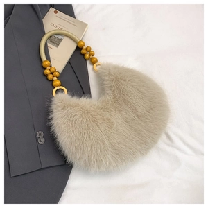 Detail of plush faux fur shoulder bag with yellow beaded handle on a blazer background