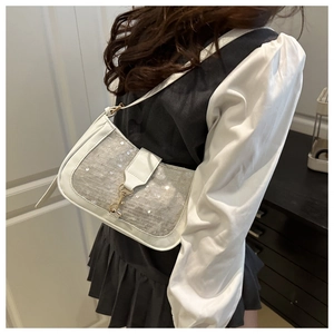 Détail du sac à bandoulière blanc avec paillettes argentées et boucle dorée sur un mannequin