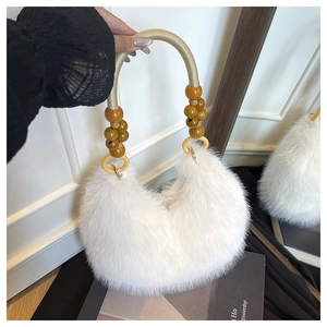 Detail of white faux fur handbag featuring unique wooden bead handle and golden hardware