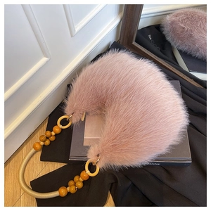 Detail of pink faux fur crescent bag featuring stylish wooden bead top handle and gold ring hardware