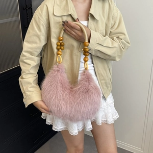 Close-up of pink fluffy plush handbag with decorative wooden bead handles and metal rings