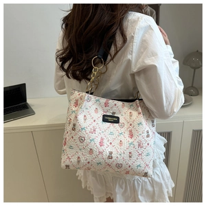 Detail of white jacquard tote bag with cartoon bear motifs and leather chain strap