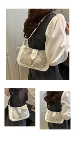 Detail of white sequin shoulder bag featuring a vintage gold metal piston lock closure