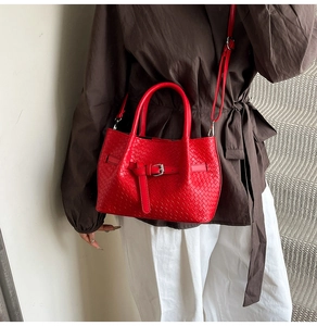 Detail of red woven texture on leather bucket bag with silver buckle and crossbody strap