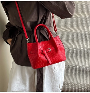 Detail of red woven leather bucket bag featuring silver metal buckle and top handles