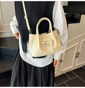 Detail of cream woven tote bag with adjustable shoulder strap and buckle on model