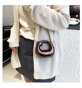 Macro view of mirror finish rose gold round crossbody bag with metal chain strap detail
