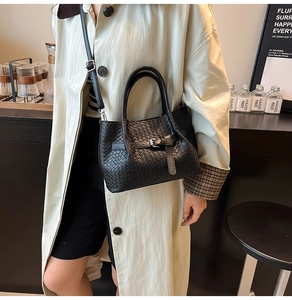 Detail of black woven leather bucket bag with metal buckle and detachable shoulder strap
