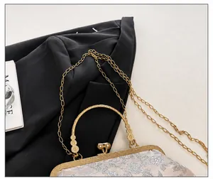 Detail of golden metal handle and fine chain strap on champagne pink satin evening bag