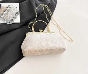 Detail of floral embroidery on a chic evening bag with pearl clasp and golden chain