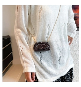 Détail du mini sac en cuir verni violet foncé avec texture ondulée et chaîne dorée