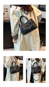 Detailed close-up of a black woven leather tote bag with decorative buckle and strap