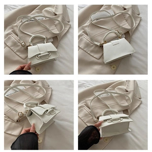 Close-up of white pebble leather mini handbag with top handle and adjustable strap