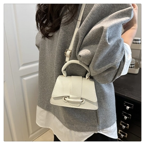 Close-up of white lychee pattern leather mini crossbody bag with ring buckle closure detail