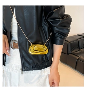 Mini sac futuriste en métal doré porté en bandoulière avec une fine chaîne d'épaule