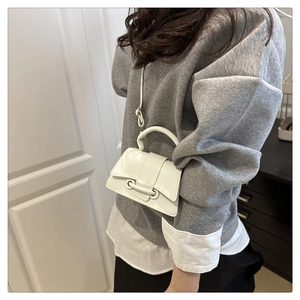Detail of white litchi pattern mini crossbody bag worn by model in home setting
