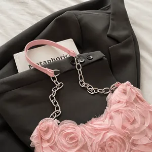 Detail of pink floral shoulder bag with contrast stitching and metal chain strap