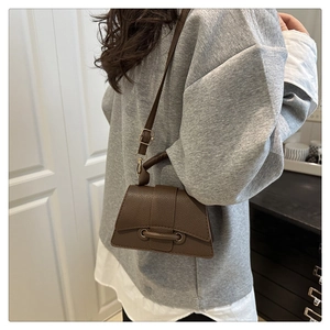 Close-up of brown litchi pattern leather hourglass bag with adjustable shoulder strap