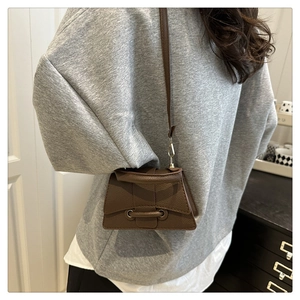 Brown litchi grain small crossbody bag with curved base and flap on female model