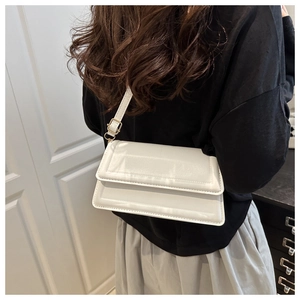 Detailweergave van een witte minimalistische crossbodytas met verstelbare riem en metalen gesp
