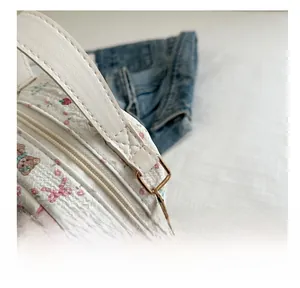 Detail of floral bear backpack featuring reinforced stitching and gold metal D-ring attachment