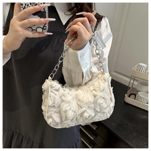Detail van witte schoudertas met 3D-bloemen en een zilveren metalen kettingriem