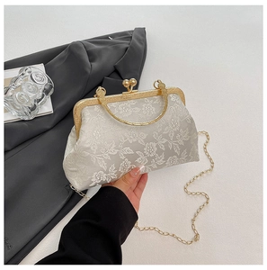 Detail view of floral embroidery and vintage metallic handle on white crossbody bag