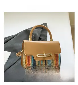 Detail of multi-color woven straw handbag with brown leather flap and gold clasp