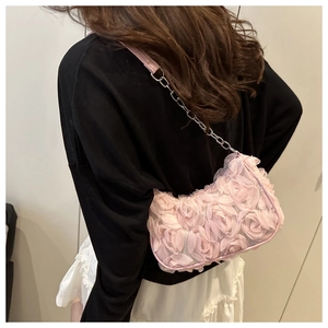 Detailed view of 3D pink fabric roses on shoulder bag with silver chain strap